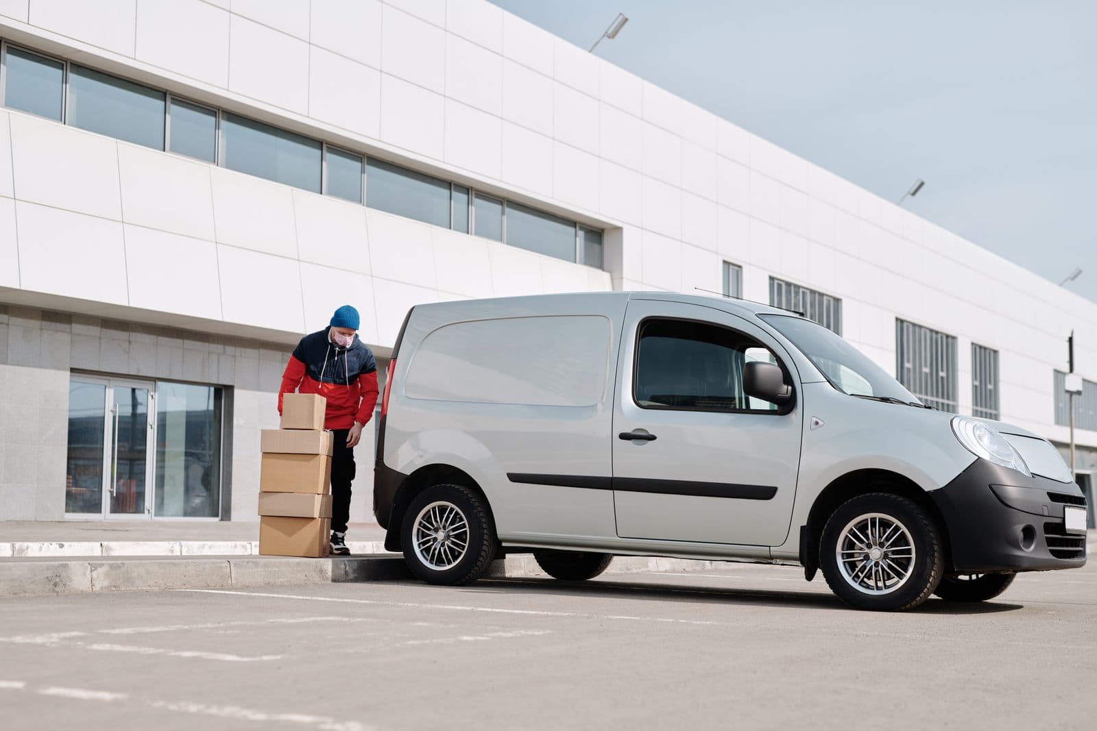 A modern panel van parked outside a building, with boxes stacked ready for delivery