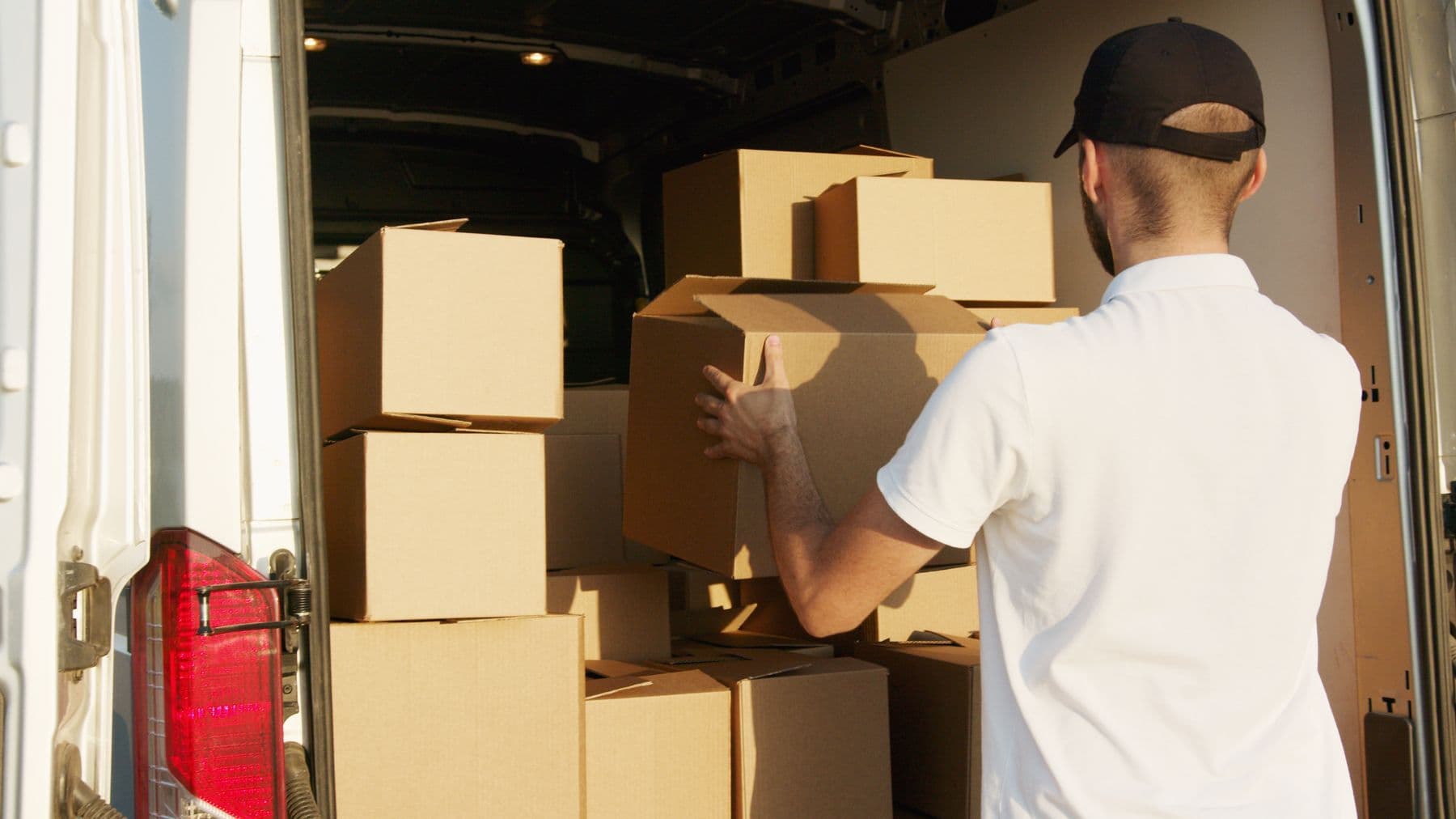 A person loading boxes into the back of a white van