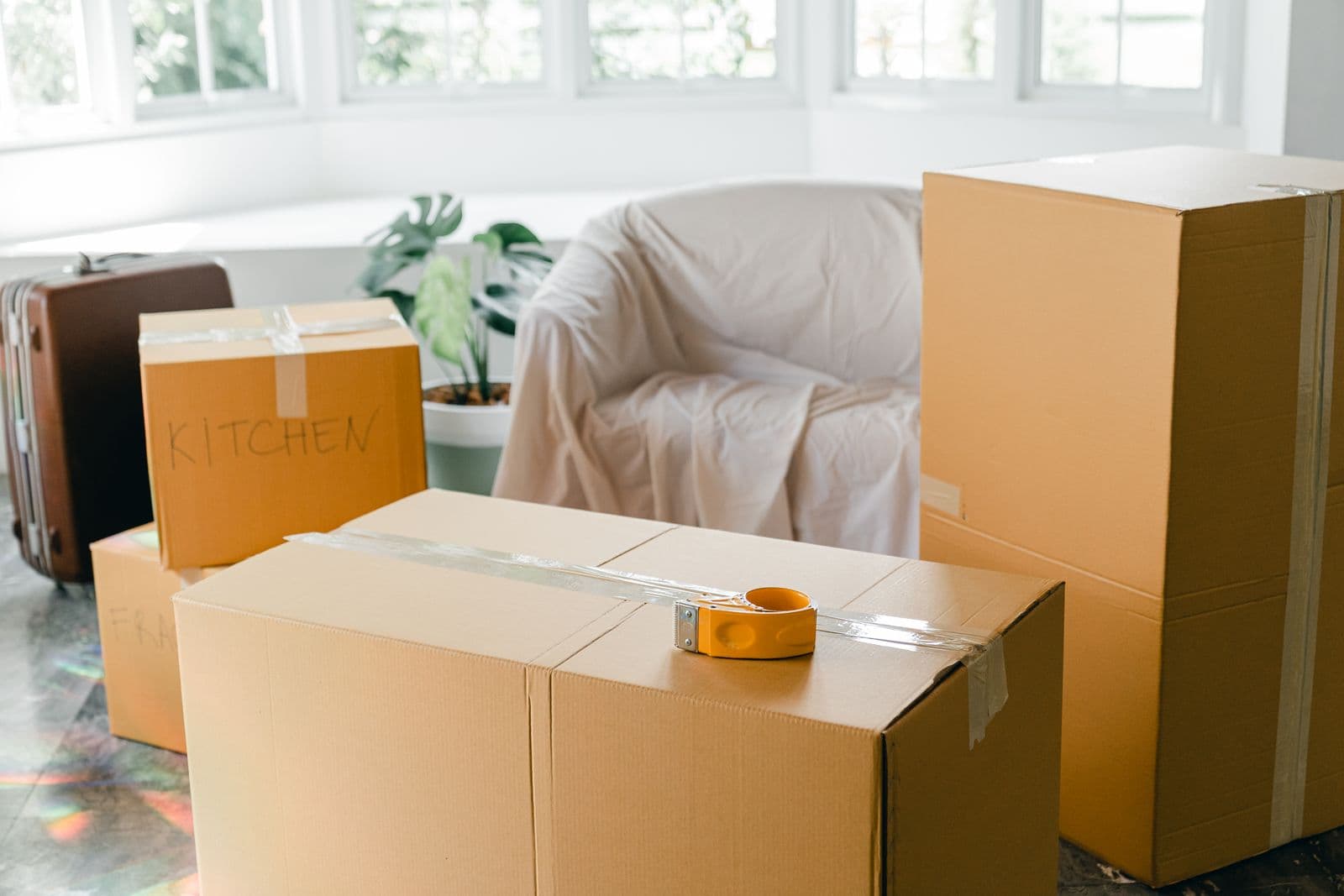 Packed boxes and a covered sofa in a bright room